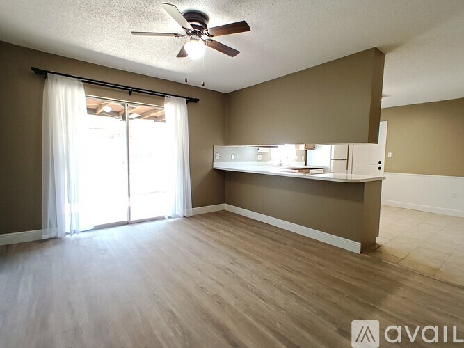 A room with a ceiling fan and sliding glass doors.