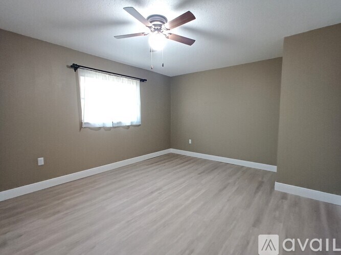 A room with a ceiling fan and a window with blinds.
