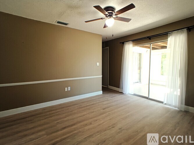 A room with a ceiling fan and sliding glass doors.