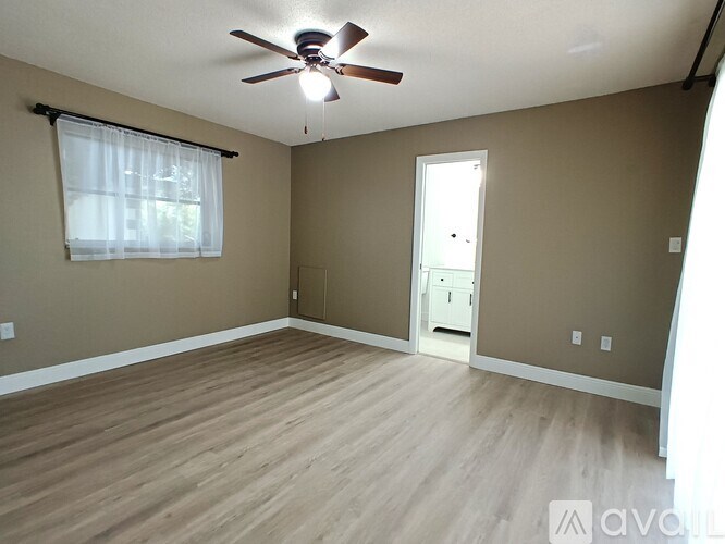 A room with a ceiling fan and light, hardwood floors, and a window with white blinds.