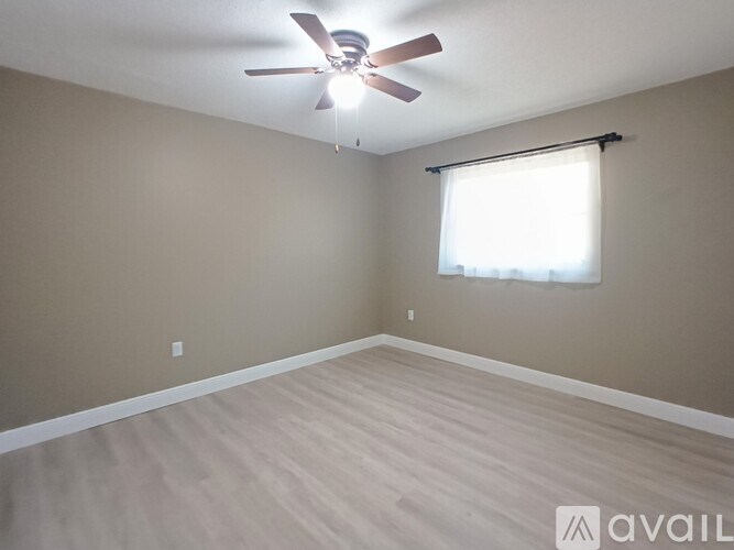 A room with a ceiling fan and a window with blinds.