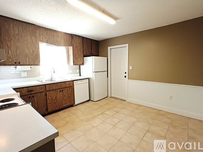 A kitchen with white appliances and brown cabinets.