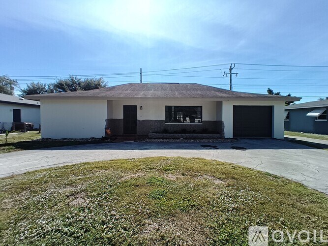A house with a grey roof and a white wall with a black door and windows.
