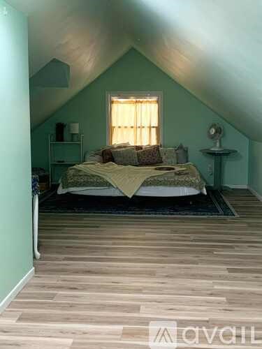 A bedroom with a bed, nightstand, and window.