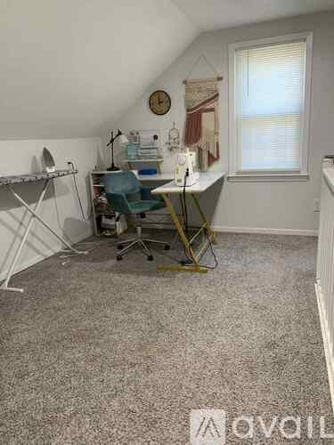 A room with a desk and ironing board in it.