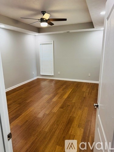 A room with wooden flooring and a ceiling fan.