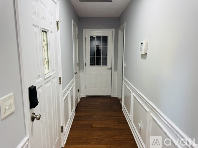 A hallway with white doors and a white wall.