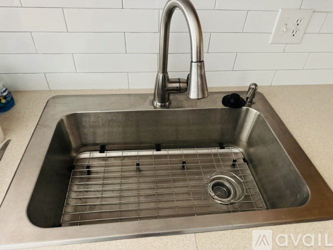 A stainless steel kitchen sink with a chrome faucet and a drain grid.