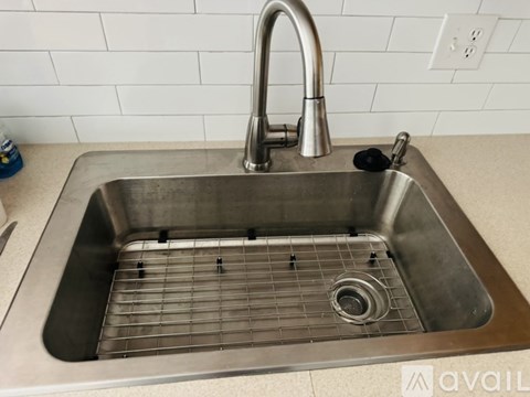 A stainless steel kitchen sink with a chrome faucet and a drain grid.