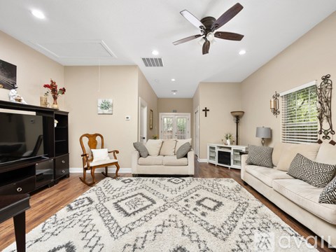 A living room with a rug, a sofa, a chair, a television and a ceiling fan.