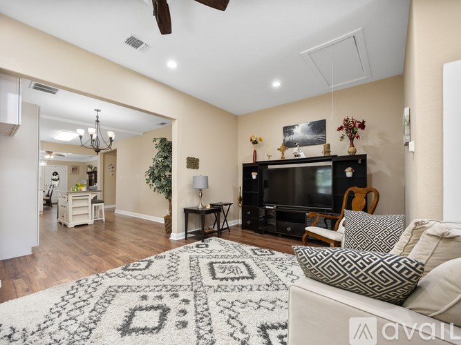 A living room with a television, a couch, and a rug.