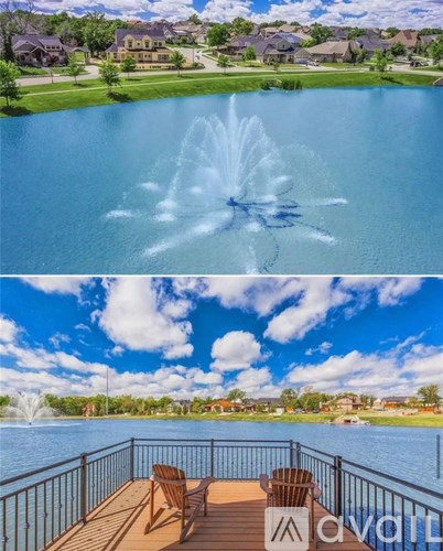A fountain in the middle of a lake with a deck and chairs in the foreground.