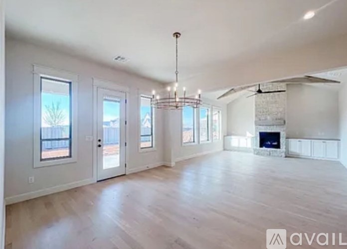 A spacious living room with a fireplace and a chandelier.