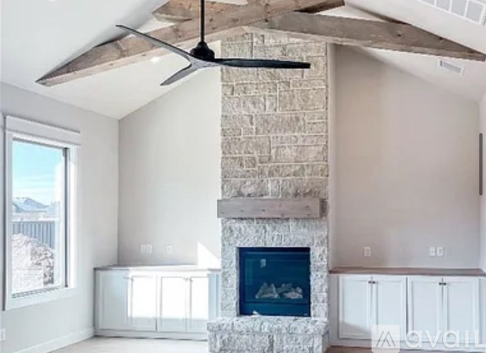 A modern living room with a stone fireplace and a ceiling fan.