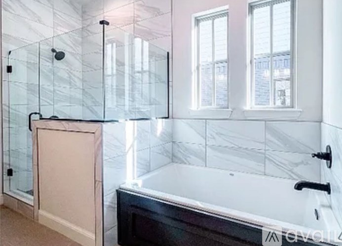 A bathroom with a black tub and a glass shower.