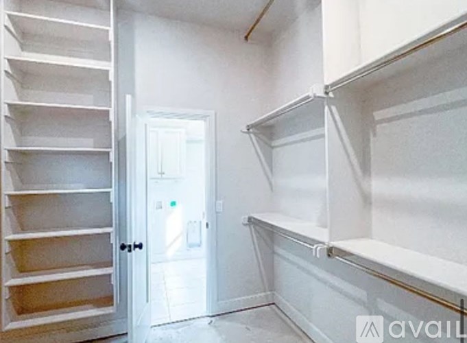 A white room with a door and a shelving unit.