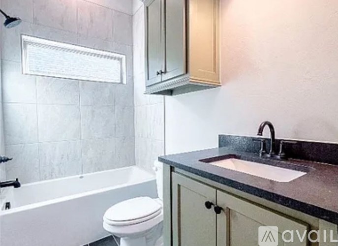 A bathroom with a white tub, sink, and toilet.