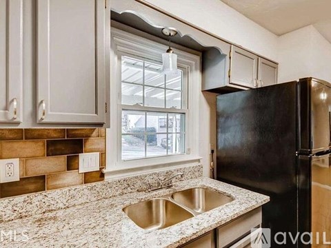 A kitchen with granite countertops and a black refrigerator.