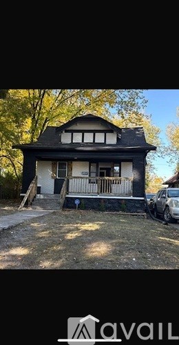 A house with a black roof and white trim is shown with a car parked in front.