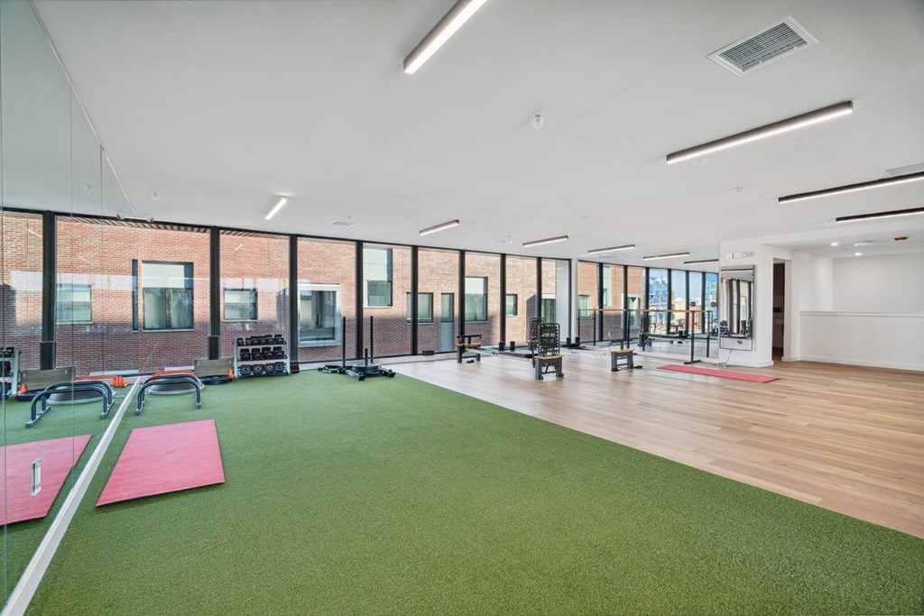 A gym with a green artificial turf and red mats.