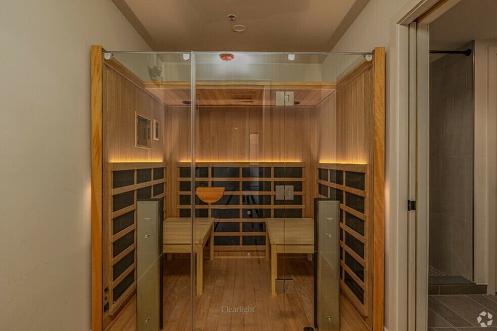 A wooden room with a glass wall and a bench.