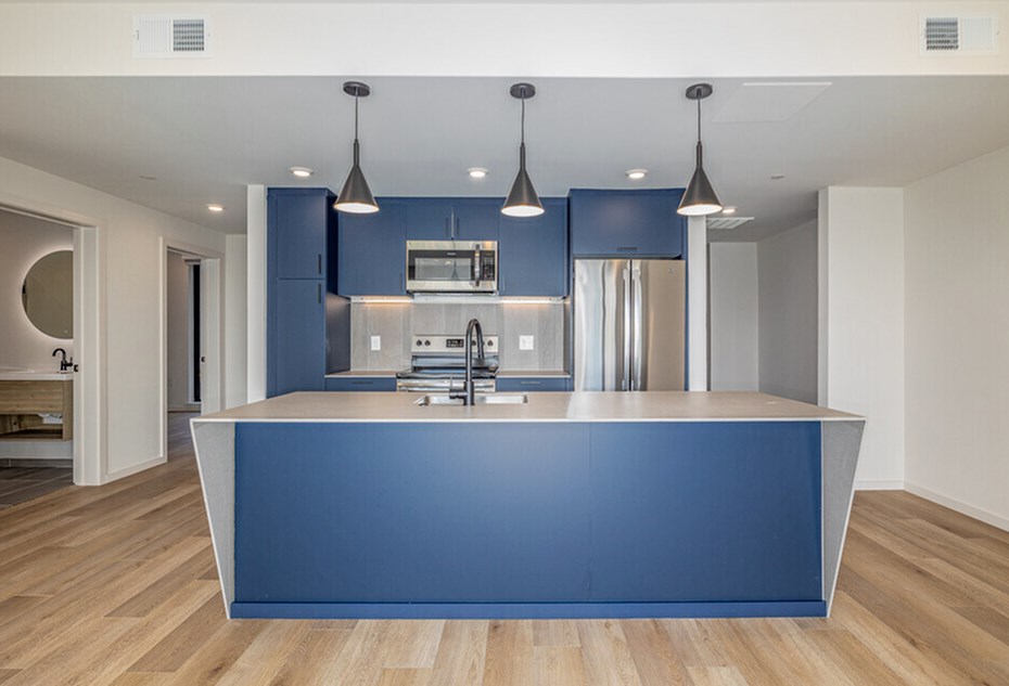 A modern kitchen with a blue island and pendant lights.