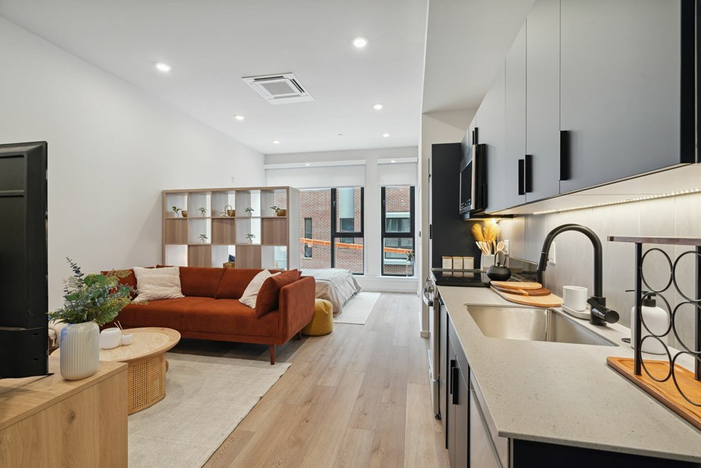 A modern kitchen with a red couch and wooden shelves.
