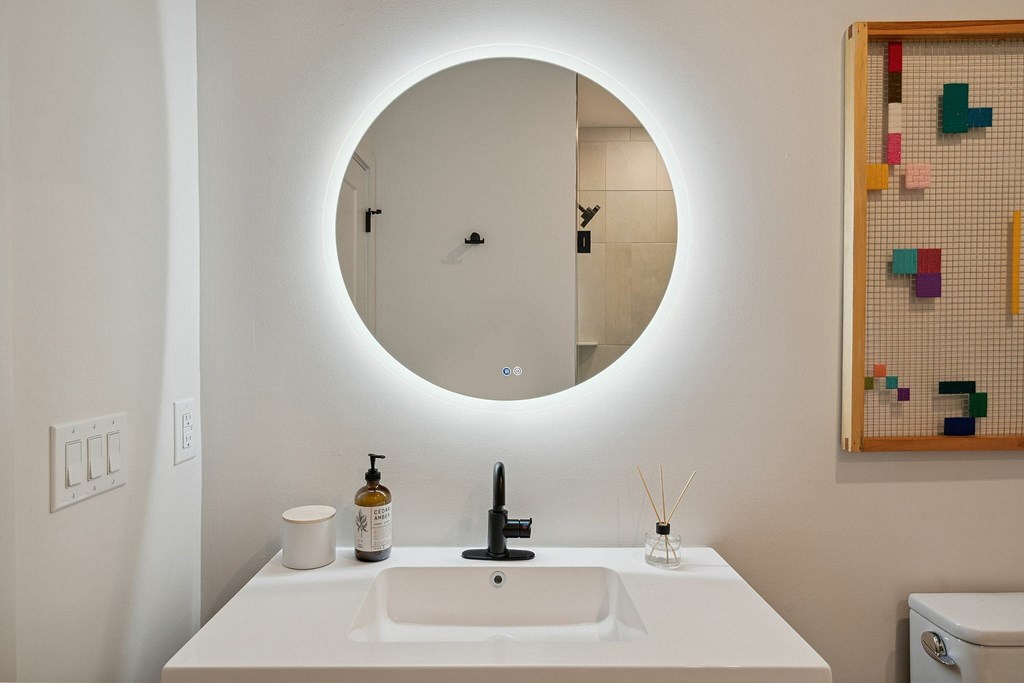 A bathroom with a round mirror and a white sink.