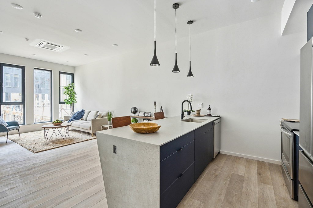 A kitchen with a white countertop and a large island with a bowl of fruit on it.