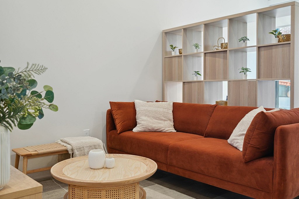 A living room with a brown couch, a wooden table, and a plant.