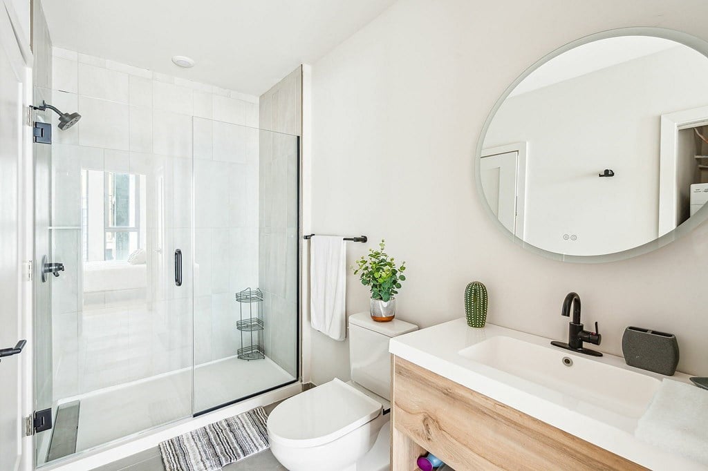 A white bathroom with a toilet, sink, and mirror.