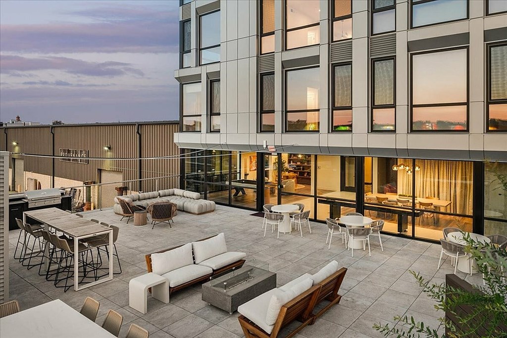 A modern outdoor seating area with a variety of furniture including tables, chairs, and couches.