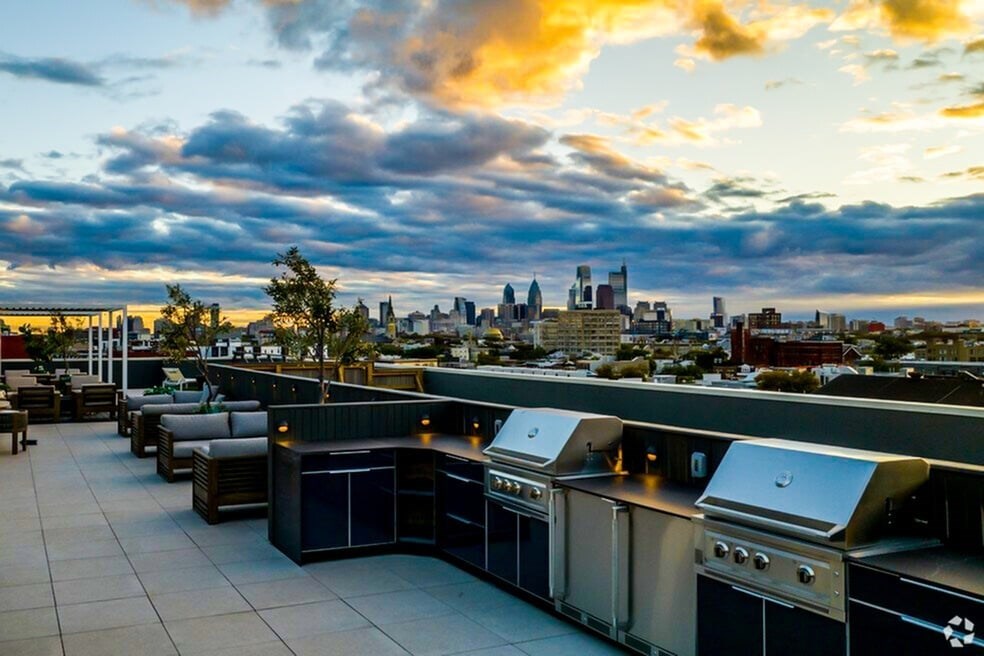 A rooftop barbecue area with grills and seating.