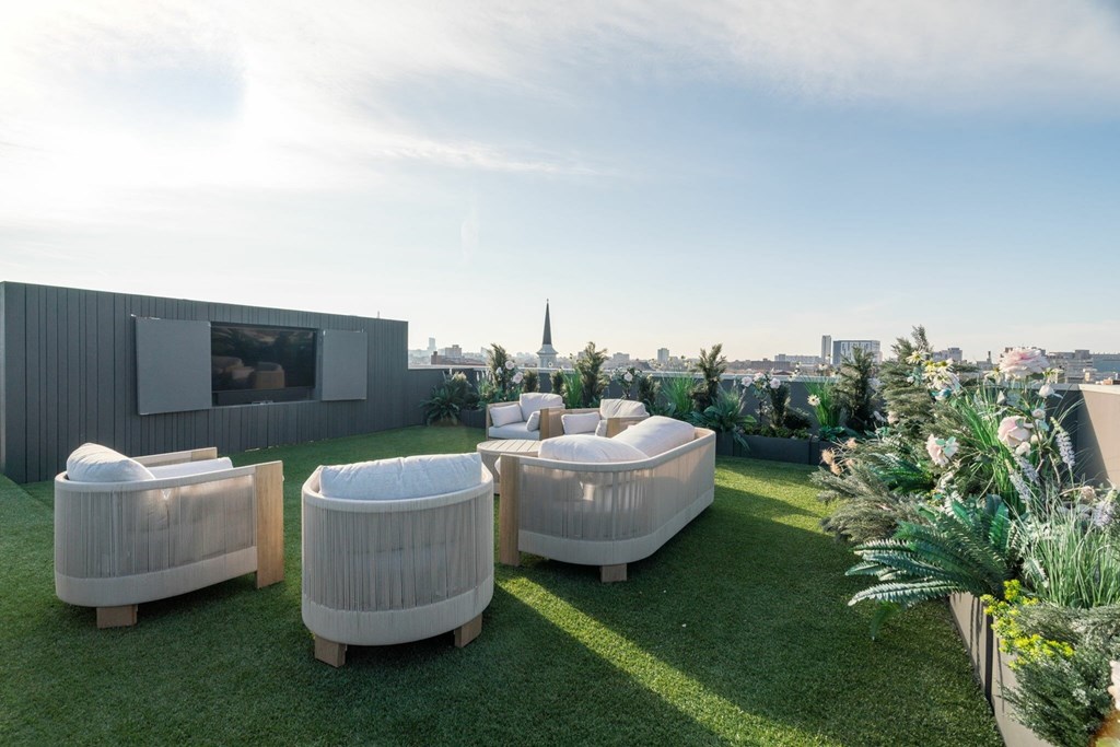 A modern outdoor seating area with white cushioned chairs and a view of the city skyline.