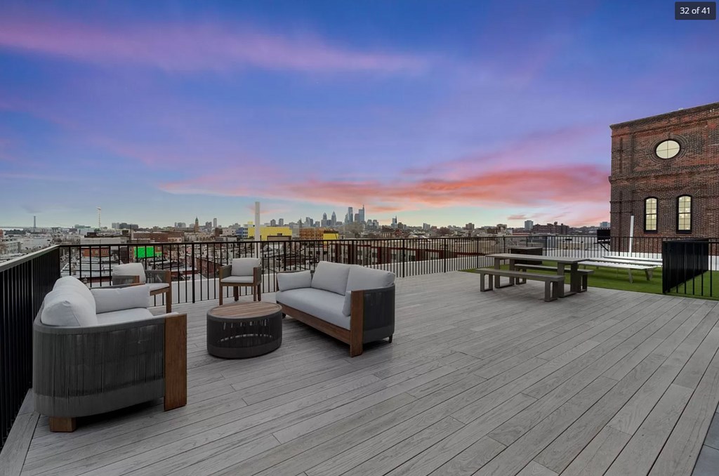 A rooftop patio with a view of the city skyline at dusk.