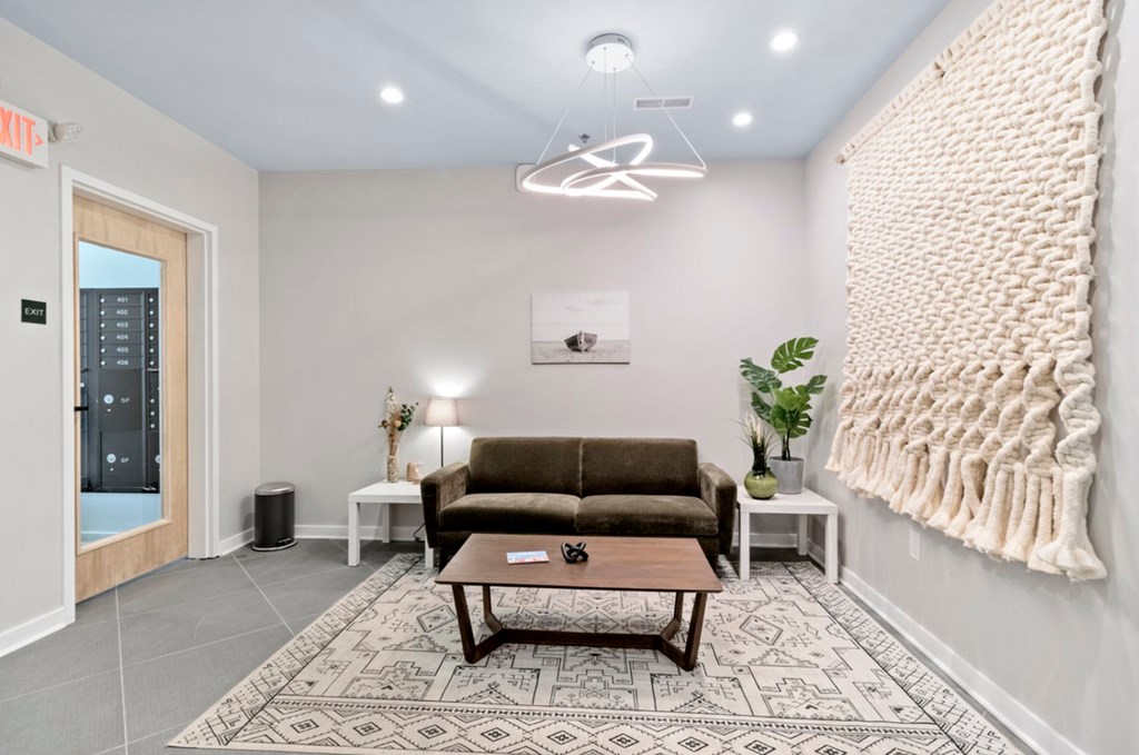 A cozy waiting room with a brown couch, a coffee table, and a large blanket on the wall.
