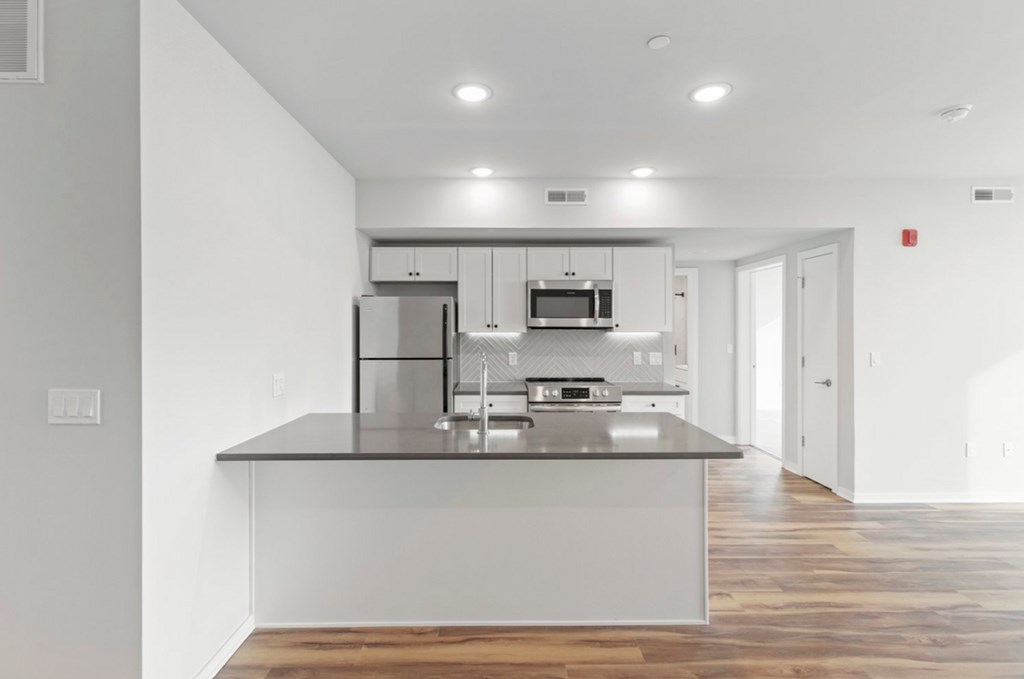 A modern kitchen with a refrigerator, microwave, and oven.