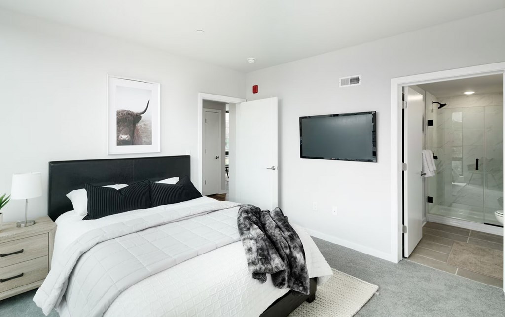 A bedroom with a large bed and a flat screen TV mounted on the wall.