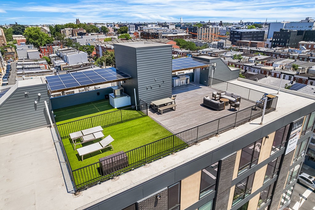 A rooftop garden with a building and a bench.