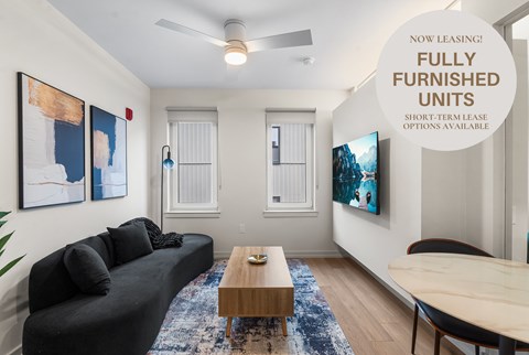 A living room with a black couch and a wooden coffee table.