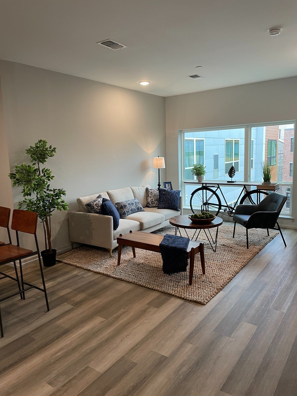 A living room with a white couch, a wooden coffee table, and a potted plant.