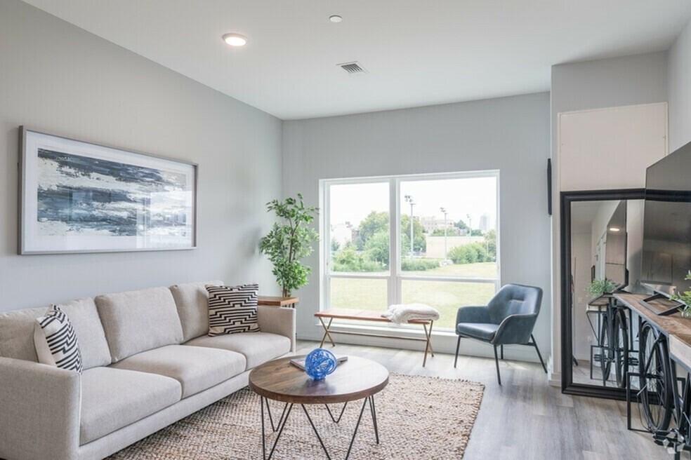 A living room with a couch, a chair, a table, and a painting on the wall.