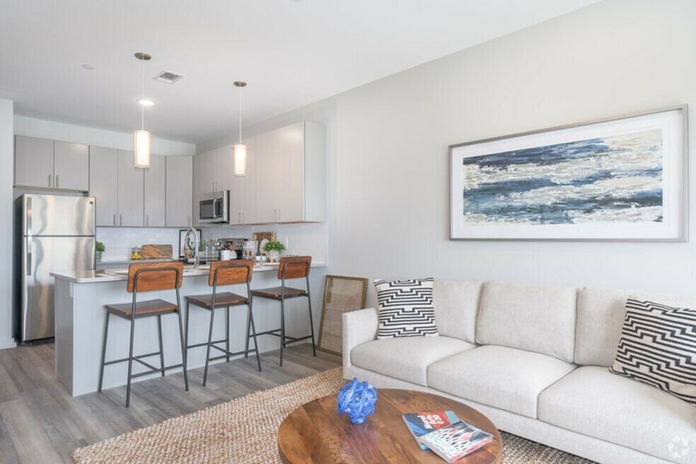 A modern kitchen with a bar and a living room with a couch.