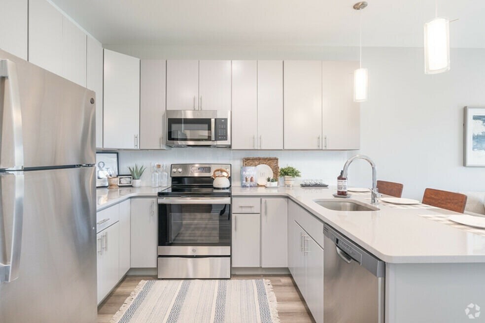 A modern kitchen with a stainless steel refrigerator and a microwave above the stove.