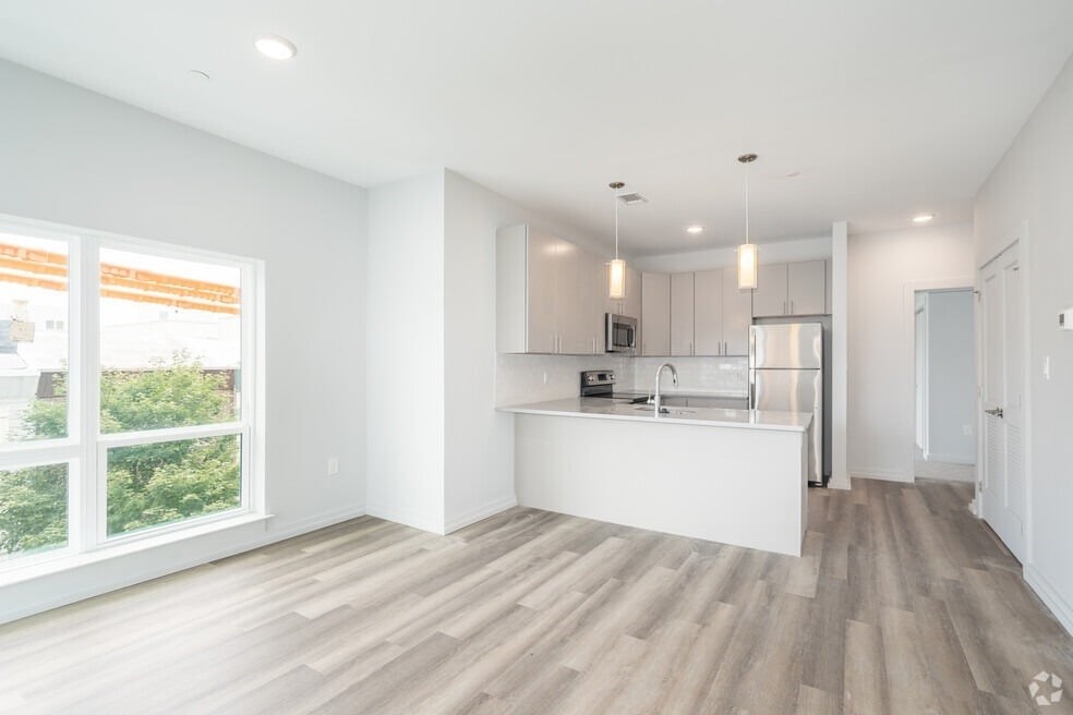 A modern kitchen with a white countertop and wooden flooring.