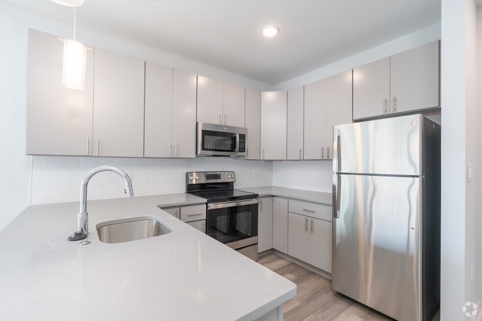 A modern kitchen with a stainless steel refrigerator, microwave, and oven.