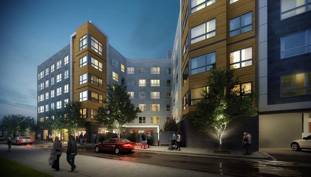 A modern apartment building with people walking on the sidewalk.