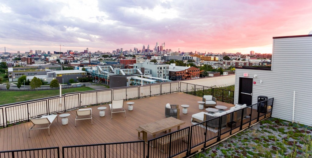 A rooftop patio with a view of the city skyline at sunset.