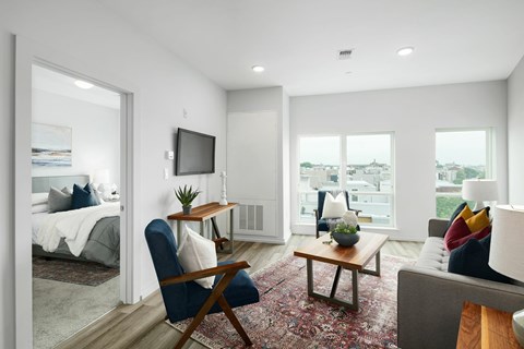 A living room with a blue chair and a flat screen TV mounted on the wall.