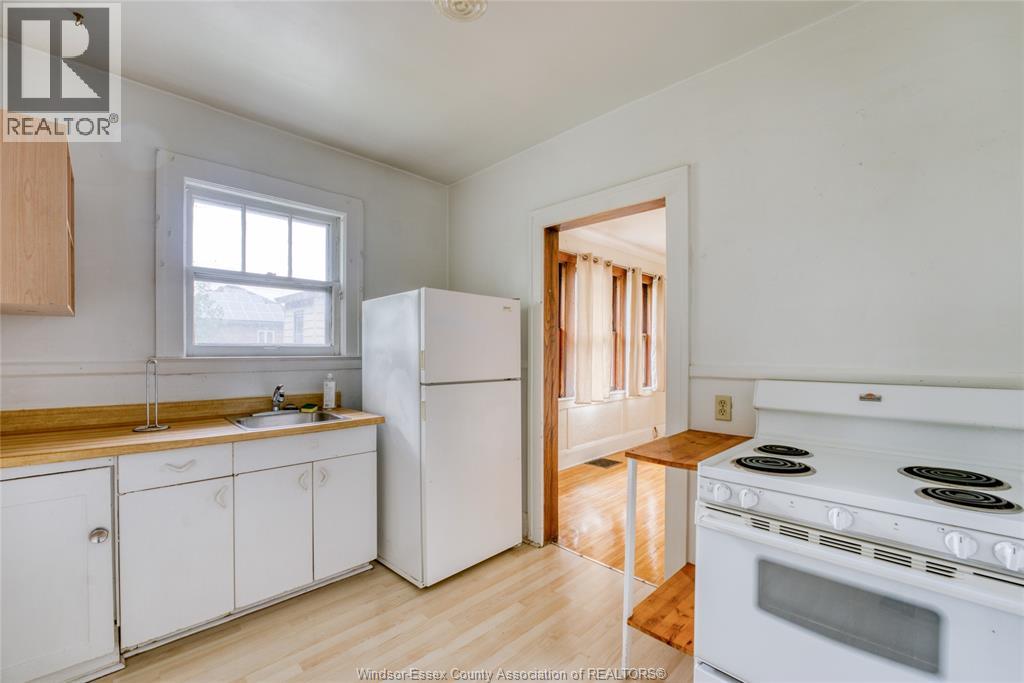 A kitchen with white appliances and wooden floors.